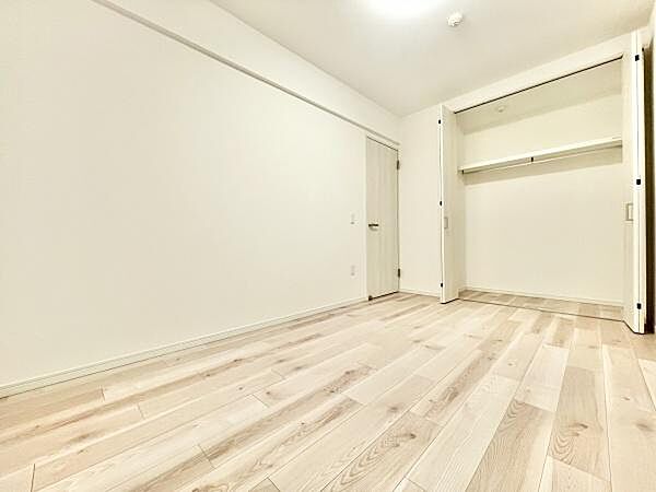 明るいフローリングが印象的な洋室です。クローゼットが備え付けられており収納スペースも確保されています。シンプルな内装でアレンジしやすいです。扉や壁も白を基調としており室内がより広く感じられます。