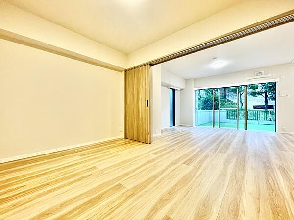 明るい色合いの床材が印象的な洋室です。引き戸で空間を仕切ることができます。大きな窓からは自然光が差し込み室内をより広く感じさせます。バルコニーへのアクセスもスムーズです。