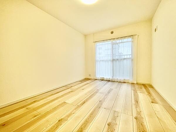 明るい色合いのフローリングが特徴的な洋室です。大きな窓から自然光が入り室内がより広く感じられます。シンプルな設計なので使い勝手も良好です。清潔感のある空間が広がっています。壁や床の状態もきれいです。