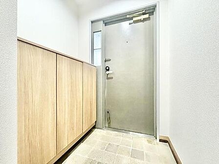 明るく清潔感のある玄関が印象的です。収納スペースも確保されており使い勝手の良い設計です。落ち着いた色合いの内装が空間を広く見せています。シンプルなデザインで幅広いインテリアに対応します。
