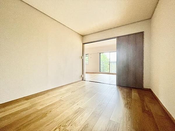 落ち着いた色味のフローリングが特徴の寝室です。スライドドアで空間を仕切ることができ使い勝手の良い造りです。隣室との一体感があるレイアウトで広がりを感じられます。開口部から自然光が入る寝室です。