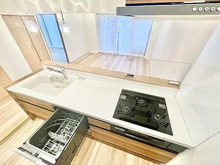 キッチンには三口コンロが備わっており調理スペースも広々としています。ビルトインタイプの食器洗浄機が設置されており日々の家事の効率化が期待できます。シンク横には十分な作業スペースが確保されています。