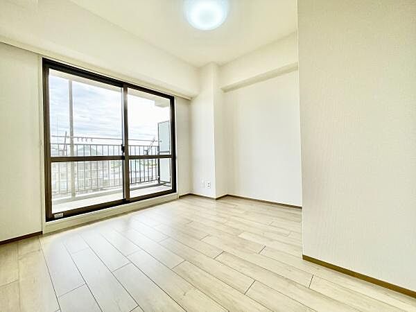 大きな窓からたっぷりと自然光が差し込む洋室です。シンプルな内装で家具のレイアウトがしやすい空間となっています。明るいフローリングがより開放的な印象を与えます。清潔感のある雰囲気が魅力です。