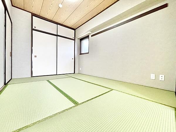 清潔感のある和室で落ち着いた雰囲気が広がります。天井や建具の木目がアクセントになっています。収納スペースも確保されており使い勝手にも配慮されています。畳の色合いが明るく部屋全体がすっきりとしています。