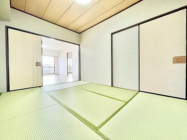 明るい雰囲気の和室です。畳の状態もきれいで清潔感があります。引き戸で空間を仕切ることができます。隣室とつながる広々とした設計です。天井や壁もシンプルな仕上がりになっています。