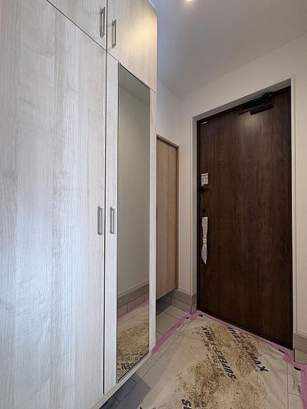 姿見付きのシューズボックスとシューズインクロークを備えた玄関。