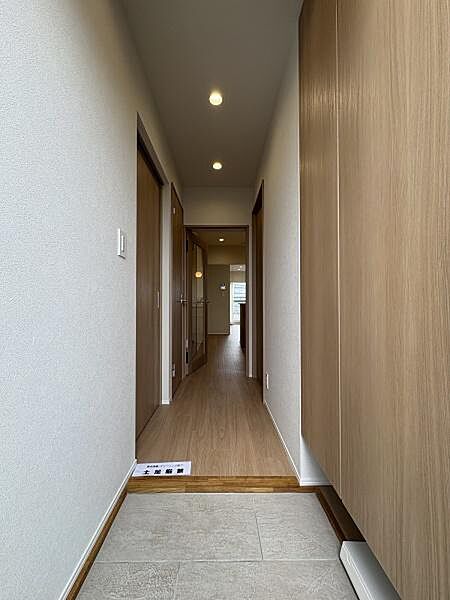 玄関を上がると、明るい木目のフローリングが奥へまっすぐ伸びています。家族を迎える入り口として気持ちよく整えられた空間です。