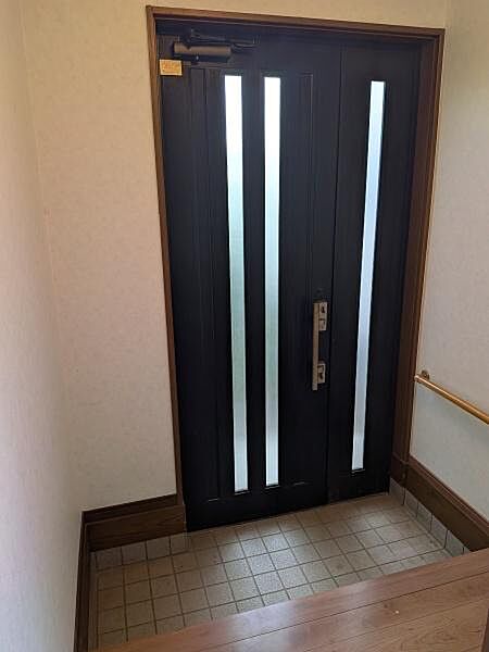 縦長の採光ガラスから自然光が差し込む玄関。ダークカラーの扉と木目の上がり框が、落ち着いた印象を演出します。壁には靴の脱ぎ履きや移動を支える手すりを設置。毎日の出入りのしやすさにも配慮された空間です。