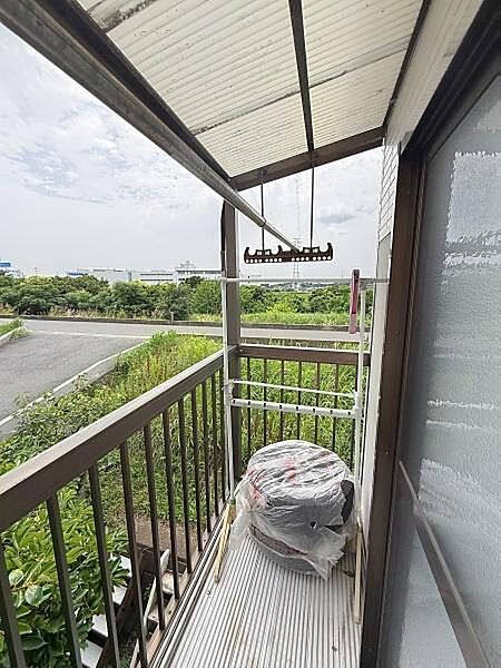 屋根付きで天候に左右されにくいバルコニーです。緑豊かな景色が広がる開放感が特徴です。物干し設備も備わっていて使い勝手の良さが感じられます。周囲の視線が気になりにくい位置にあります。
