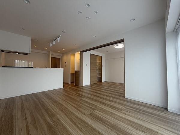 開放的な空間が広がるリビングです。木目調フローリングが落ち着いた印象を与えます。室内は明るく窓からの光がしっかり届きます。可動式の仕切りで空間を柔軟に使えます。収納スペースも確保されています。