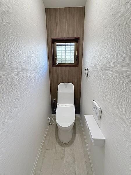落ち着いた色合いの壁面が印象的なトイレです。小窓が設置されており明るさと換気が確保されています。清潔感のあるシンプルなデザインで使いやすさも感じられます。床材とのコントラストもポイントです。