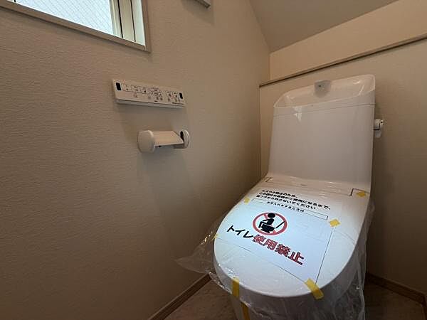 窓が付いており換気もしやすいトイレです。シンプルなデザインで清潔感があります。壁面に操作パネルがあり使い勝手に配慮されています。ペーパーホルダーも設置済みです。