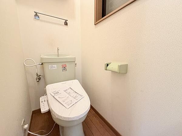 シンプルな設計のトイレで掃除がしやすいレイアウトです。換気用の窓が設置されており明るい空間が広がります。ペーパー収納も壁面に配置されています。温水洗浄機能が備わっています。