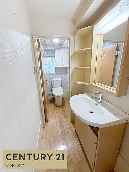手洗いスペースとトイレが程よく分かれたすっきりとしたレイアウトです。明るい内装と木目調の床が空間全体にあたたかな印象を与えます。収納棚付きで洗面小物の整理にも役立ちます。