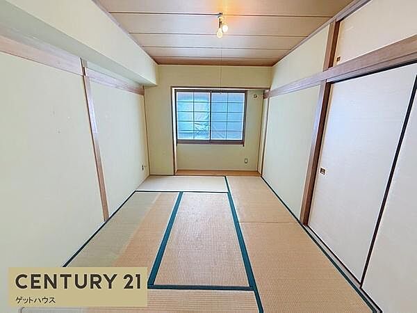 窓から自然光が入り明るさが感じられる和室です。押し入れの収納スペースも確保されています。畳敷きの心地よい空間です。天井や壁の木目が落ち着いた印象を与えます。