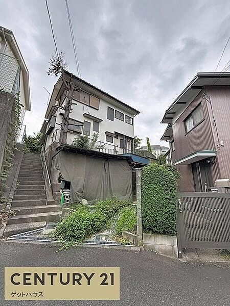 前面道路から物件までのアクセスを確認できる写真です。周囲は住宅が建ち並ぶ落ち着いた環境です。敷地前には階段がありプライバシーにも配慮された立地となっています。植栽も整えられ外観の印象を引き立てます。