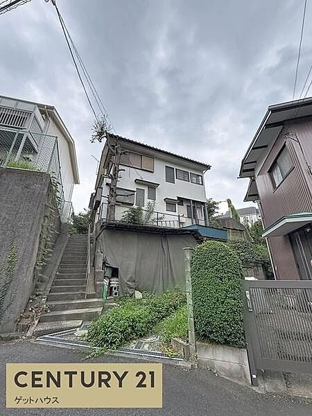 現地前面道路からの様子が一目でわかる写真です。敷地までの階段や周辺の住環境が確認できます。現地の雰囲気や周囲の建物との距離感もご覧いただけます。建物外観の状態もチェックしやすい一枚です。