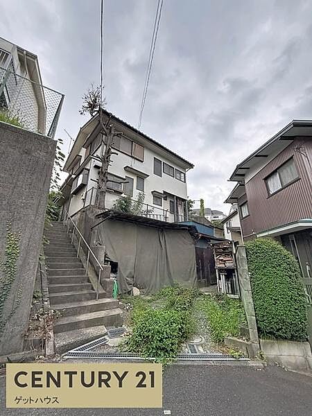 前面道路に面しており住まいへのアクセスがスムーズに感じられます。階段を上がった先の住宅は個性的な佇まいです。周辺には住宅が立ち並び落ち着いた雰囲気の街並みです。