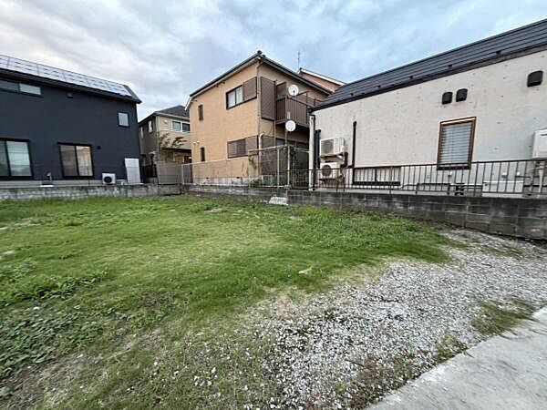 敷地内は広々としたスペースが確保されており様々な用途に活用できます。周囲には住宅が並び落ち着いた環境が感じられます。敷地の一部には芝生が広がり手入れのしやすい土地形状です。