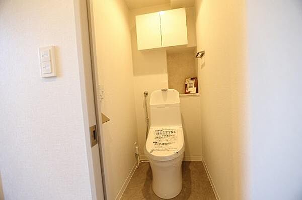トイレはシンプルなデザインながら、使いやすい温水洗浄便座が設置されております。また、上部には便利な棚が備わっております。