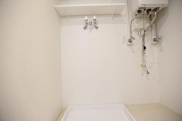 洗濯機置き場には、防水パンおよび洗濯機用水栓を備えております。また、上部には収納に便利な棚を設置しております。