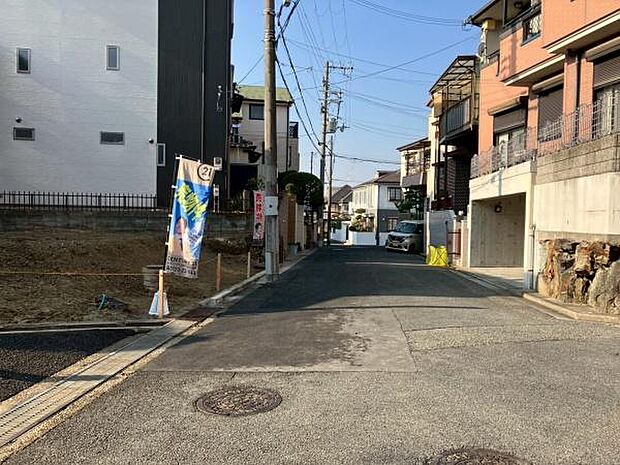 閑静な住宅街に位置し前面道路も広くお車の出入りがしやすい環境です。周囲には住宅が並び落ち着いた雰囲気が広がります。整備された歩道や電柱があり日当たりの良い街並みとなっています。