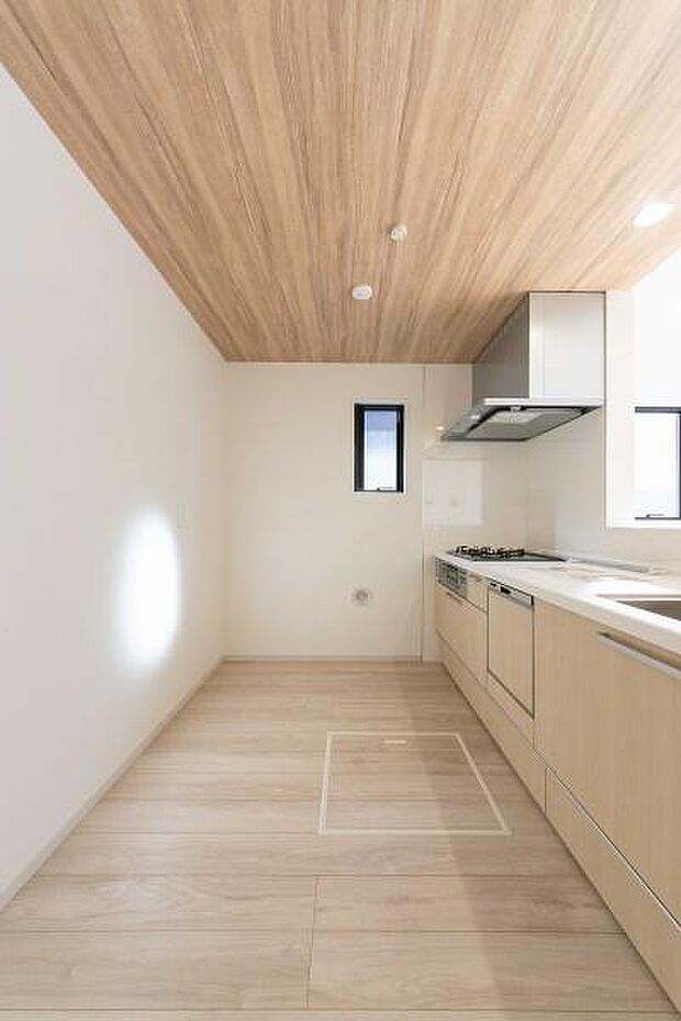 木の温もりに包まれる開放的なキッチン。木目調の天井が心地よい空間を演出し、料理中もリビングの家族と笑顔で繋がれる住まい。