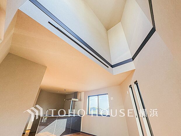 天窓から降り注ぐ自然光が、吹抜けの開放的な空間を照らします。穏やかな光に包まれた上質な居住空間です。