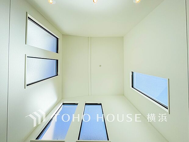 天窓から降り注ぐ自然光が、吹抜けの開放的な空間を照らします。穏やかな光に包まれた上質な居住空間です。