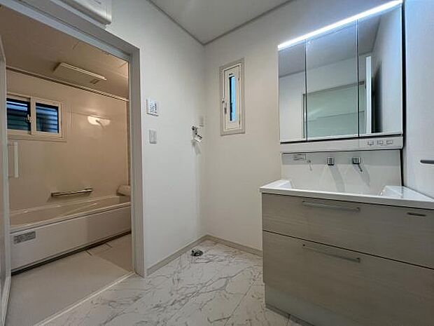 三面鏡付き洗面化粧台。合わせ鏡で後ろのスタイリングも快適。鏡の後ろは収納になっているので、細々したものを収納でき、スッキリとした洗面回りに。