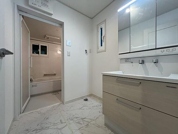 三面鏡付き洗面化粧台。合わせ鏡で後ろのスタイリングも快適。鏡の後ろは収納になっているので、細々したものを収納でき、スッキリとした洗面回りに。