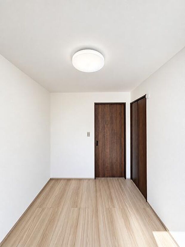 落ち着いた木目の建具と明るいフローリングが調和した洋室。シンプルな内装で家具配置もしやすく、寝室や子ども部屋、在宅ワーク用の個室など幅広く活用できます。収納扉も備え、室内をすっきり保てます。