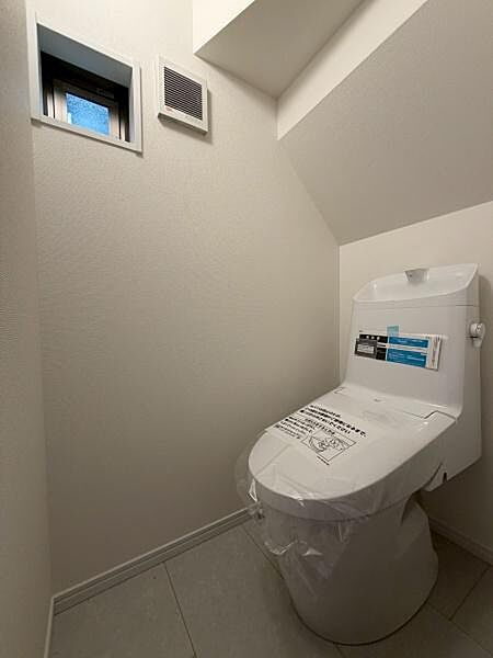 トイレ空間が明るく清潔感があります。換気用の窓と通気口があり快適性が感じられます。ゆとりのある設計で使いやすさにも配慮されています。シンプルで落ち着いた雰囲気が魅力のトイレです。