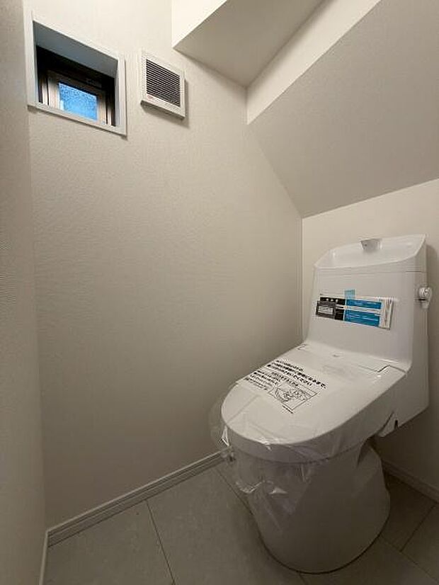 トイレ空間が明るく清潔感があります。換気用の窓と通気口があり快適性が感じられます。ゆとりのある設計で使いやすさにも配慮されています。シンプルで落ち着いた雰囲気が魅力のトイレです。
