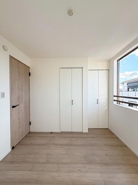 明るい日差しが差し込む洋室です。シンプルな内装でインテリアも合わせやすく使い勝手の良い空間となっています。クローゼットも備わっており収納力も確保されています。木目調のドアが温かみを感じさせます。