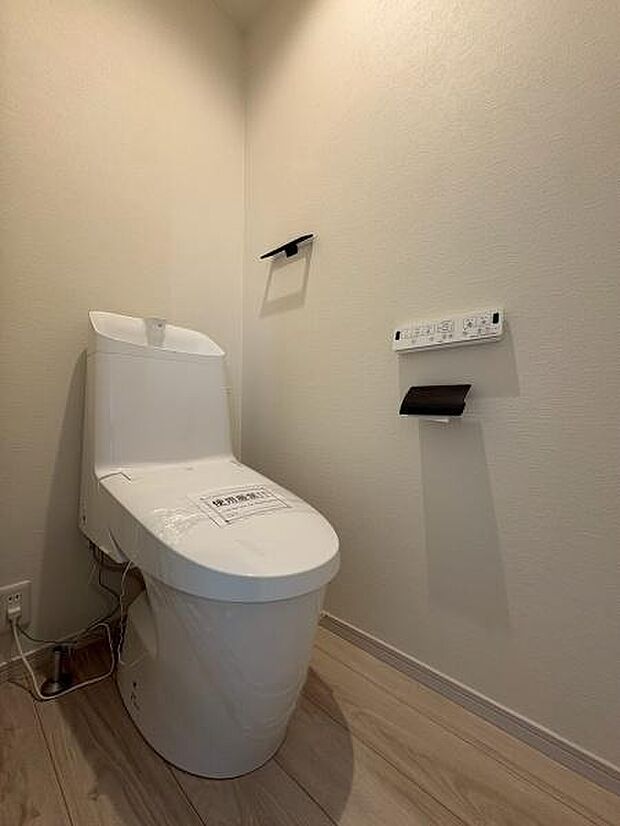 清潔感のあるシンプルなデザインのトイレです。床は明るい木目調でお手入れもしやすい仕様となっております。コンセントの配置も便利に設計されています。