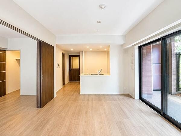 大きな開口部から専用テラスへつながる開放感のあるLDK。明るい木目調の床と白を基調とした内装が爽やかな印象です。洋室との間仕切りを開放すれば、さらに広がりを感じられます。