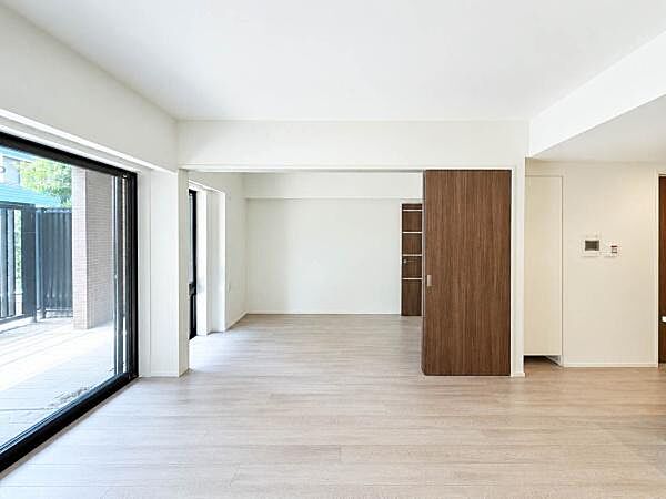 専用テラスに面した大きな窓から光を取り込むLDK。隣接洋室との一体利用も可能で、生活スタイルに合わせて空間を柔軟に使えます。落ち着いた内装で家具やインテリアも合わせやすい空間です。