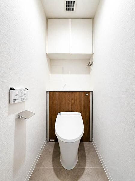 すっきりとしたデザインの温水洗浄便座付きトイレ。上部には収納スペースも設けられ、トイレットペーパーや清掃用品を目立たせず保管できます。清潔感と使いやすさを備えた空間です。