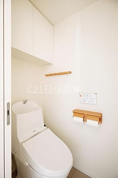 シンプルで清潔感のあるトイレです。収納スペースも設けられており使い勝手に配慮されています。壁面の収納棚やペーパーホルダーが便利に配置されています。落ち着いた雰囲気の空間となっています。