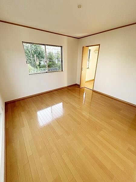 明るい日差しがたっぷりと差し込む洋室です。床は落ち着いた色合いのフローリング仕様で清潔感があります。大きめの窓が開放感を演出しています。シンプルな内装は様々なインテリアと調和します。