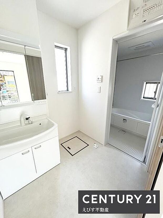 明るい空間が広がる洗面所です。白を基調としたシンプルな内装が清潔感を演出しています。収納も備わっており機能性に優れています。浴室への動線もスムーズです。窓から自然光も入ります。