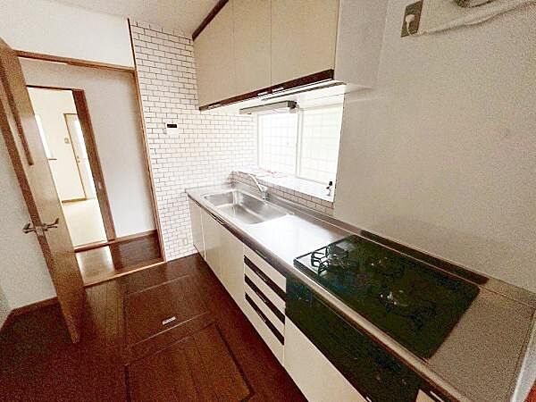 明るい窓から自然光が差し込むキッチンです。白を基調としたデザインが清潔感を演出します。壁のタイルがアクセントになっています。作業スペースも広く使いやすい印象です。