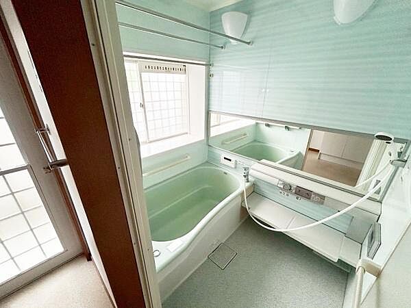 広々とした浴室で窓から自然光が入る明るい空間です。ミラーや棚も備わり使い勝手の良さが感じられます。清潔感のあるデザインが特徴的です。浴槽もゆったりとしたサイズとなっています。