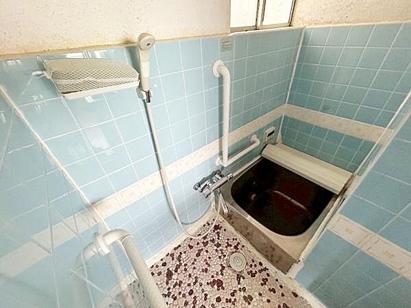 レトロなデザインのタイルが印象的なバスルームです。浴槽には蓋が付属しており使い勝手の良さが伺えます。壁付けのシャワーと手すりも設置されています。床は滑りにくい仕様です。