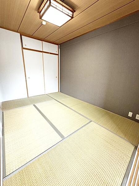 【一部AIモノ消し済み・実際の室内状況優先】落ち着いた色合いの壁と畳が調和する和室です。収納付きで使い勝手の良いスペースになっています。明るい照明が室内全体をしっかりと照らします。