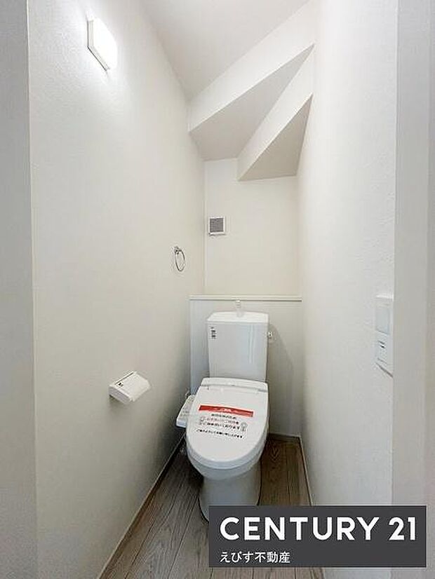 シンプルで清潔感のあるトイレ空間です。壁や床の色調が落ち着いた雰囲気を演出しています。照明も明るく快適にご利用いただけます。スペースが有効に活用されています。収納や手洗いも便利にお使いいただけます。