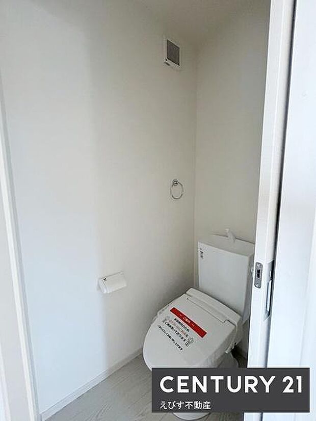 シンプルで清潔感のあるトイレ空間です。壁や床の色が明るく圧迫感を感じにくい設計です。ペーパーホルダーやタオルリングも使いやすい位置に配置されています。換気設備も設置されており快適にご利用いただけます。