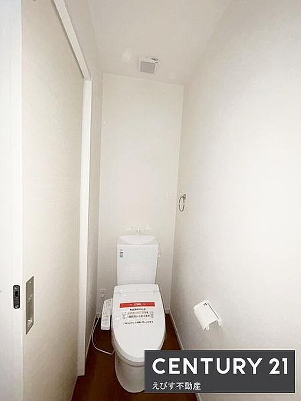 シンプルなデザインで清掃もしやすいトイレ空間です。壁紙と床の色合いが落ち着いた雰囲気を演出します。換気扇が設置されているため空気の循環も安心です。