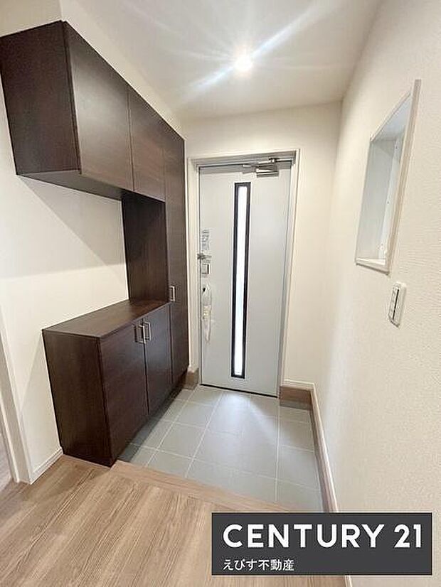 明るい玄関スペースが印象的です。収納が豊富で整理しやすい設計になっています。シンプルなドアデザインが空間を引き締めています。床の色調も落ち着いており清潔感があります。使い勝手にも配慮された玄関です。